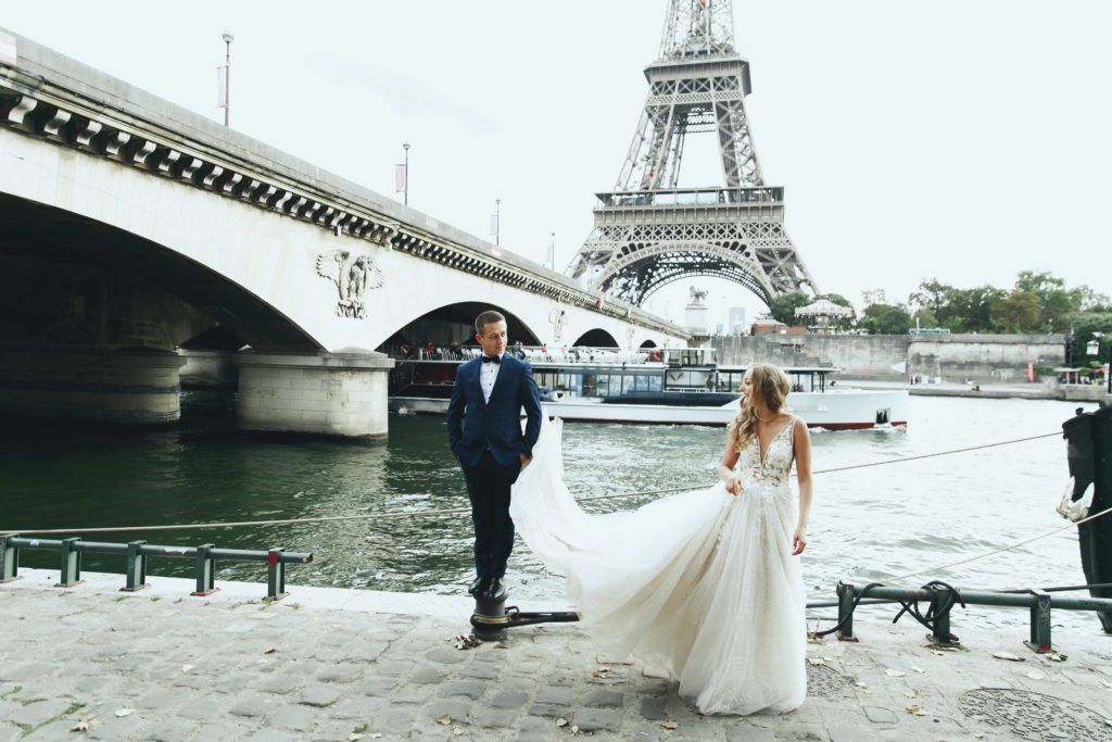 Luxury wedding couple poses before river Seine and the Eiffel Tower somewhere in Paris